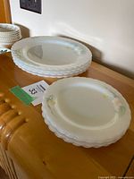 Stack of seven larger dinner plates showing scalloped edges and floral pattern