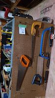 Pegboard with multiple hand saws, hacksaw partly visible