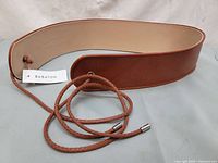 Full view of Babaton cognac leather belt with braided tie and metal tips