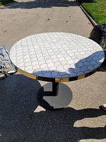 Side view showing full table, marble top pattern, gold rim, black base