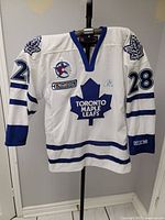 Full front view showing jersey, number 28, logos, and autograph placement