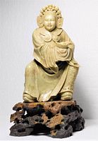 Front view of carved hard stone figure on stand