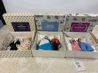 Three Peggy Nisbet boxed sets opened showing dolls and certificates