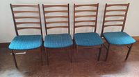 Front view of four teak dining chairs in a row