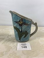 Front view of stoneware pitcher showing floral design and form