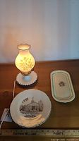 Overall view of milk glass lamp, round collector plate and rectangular Staffordshire plate
