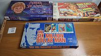Closed boxes of the three board games: Murder She Wrote, The Fall Guy, The Six Million Dollar Man.