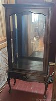 Front view of walnut display cabinet showing glass door, mirrored back and drawer