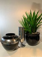Group view of artificial plant in planter, round vase, and metal vase