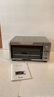 Front view of Breville Mini Smart toaster oven with manual placed in front