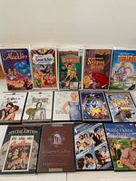 Full lot showing five Disney VHS tapes back row and nine DVDs front row