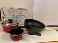 Full lot showing four glass containers, red lidded saucepan, small red pot, black frying pan