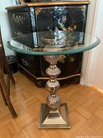Full view of side table showing base, glass orbs, square foot, surrounding furniture for scale
