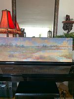 Full view of pastel landscape canvas resting on piano, shows entire artwork and scale