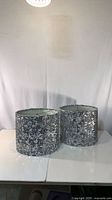 Front view of both silver sequin drum lamp shades