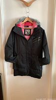 Front view of Oakley black 3/4 length jacket hanging, showing hood with faux fur trim