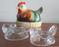 Ceramic hen on basket with two clear glass hen egg cups