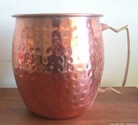 Front view showing hammered copper body and brass handle