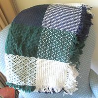Folded throw showing patchwork squares and fringe