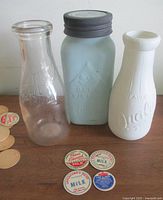 Group shot of three bottles and several milk bottle caps on tabletop