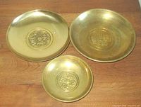 Three brass dishes displayed top view to show coin symbols and size difference