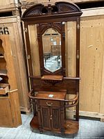 Front view of mahogany inlaid hall stand showing mirror, hooks, shelves, cabinet and umbrella holders