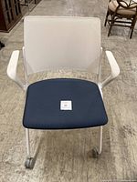 Front view of white office chair with blue seat cushion and casters