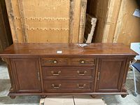 Full front view of wooden sideboard showing drawers, doors, hardware, carved details