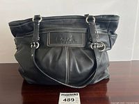 Front view of black leather Coach handbag on table