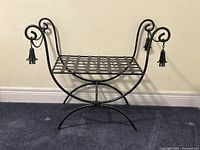 side view of wrought iron bench showing lattice seat and three tassels