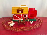 Overall view of barn, silo, figures, animals, and fence