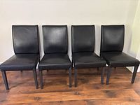 Front view of all four black leather dining chairs aligned