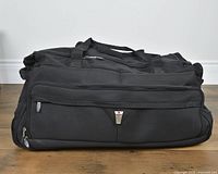 Front view of black Delsey wheeled duffel showing exterior pocket and logo