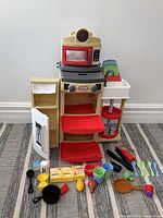 Front view of play kitchen fully open with accessories laid out