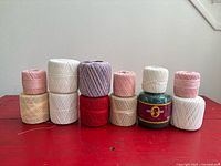 All twelve crochet thread balls arranged upright on red surface