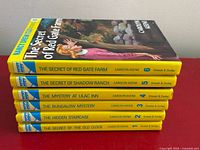 Stacked view of all six Nancy Drew yellow-spine volumes showing titles and cover of Vol. 6