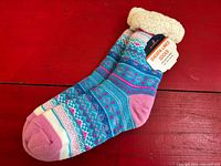 Pair of multicolor sherpa-lined slipper socks on red surface