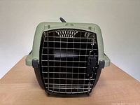 Front view of carrier showing metal wire door, tan top, black base, handle