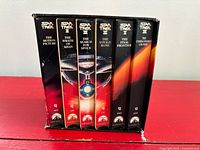 Front view of six VHS tapes in slipcase showing titles and spines