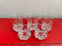Front view of five pressed glass tumblers showing shape and base design