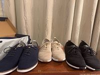 Three pairs of Cole Haan knit lace-up shoes on table with boxed pair at left edge