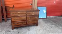 Front view of walnut dresser with brass hardware, mirror leaning behind
