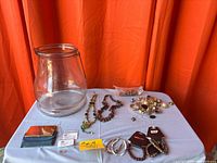 Group shot showing glass jar, necklaces, bracelets, compact, packaged charms