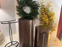 Group shot of both trash cans, towel holder, wreath and yellow floral spray