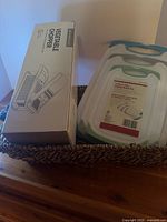 Boxed vegetable chopper and cutting boards inside woven basket