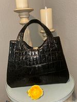Front view of black alligator handbag showing overall design