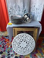 Group shot of stacked plates, wolf figurine, medallion plaque and mirror