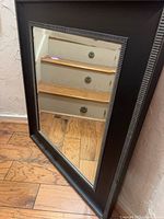 Full front view of rectangular beveled mirror with black frame and silver accent
