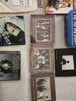 Multiple CD albums and Beatles puzzle tin on table