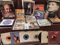 Overall lot with books at back, row of CDs and cassettes, 45 rpm records front